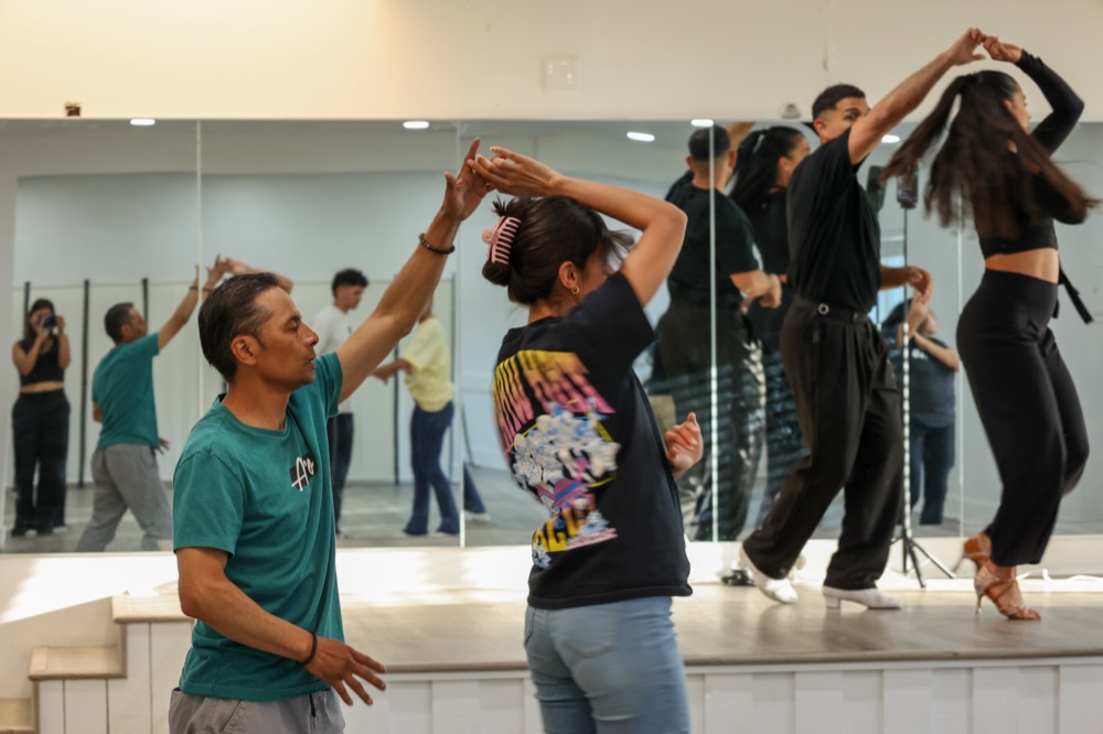 Students practicing Salsa turns in the bright Latin Dance Utah studio.