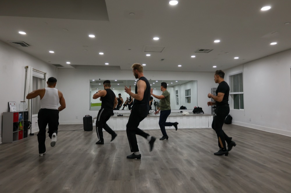 Dancers practicing timing and footwork across the studio floor.